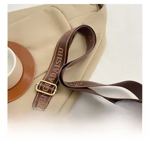 Detail of adjustable woven nylon shoulder strap and gold hardware on black leather bag