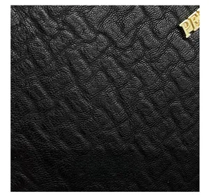 Close-up of black textured leather on Boston bag with gold metallic logo detail