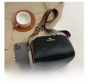 Close-up of black woven leather texture with gold kangaroo logo and wide fabric strap