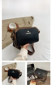 Detail view of woven black Boston bag with brown leather accents and branded wide strap