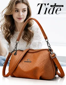 Détail du sac à bandoulière en cuir grainé orange porté avec un haut en dentelle blanche
