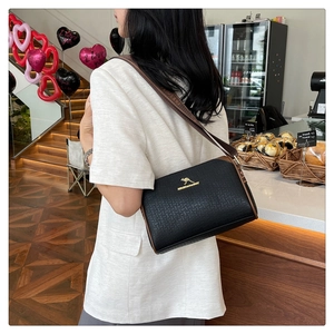 Detail of black textured leather bag with gold kangaroo logo and adjustable brown strap