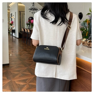 Black pebbled leather Boston bag detail featuring golden kangaroo logo and woven strap