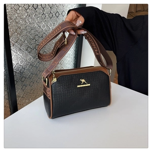 Detail of Boston bag with black woven texture, brown trim and wide shoulder strap