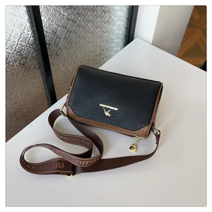 Detail of vintage black textured leather crossbody bag with golden kangaroo emblem