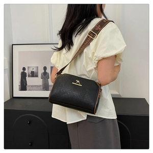 Detail view of black textured Boston bag with wide logo strap and golden kangaroo emblem