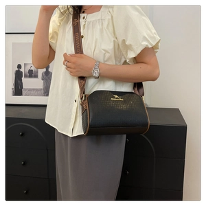 Detail of black textured Boston bag with golden kangaroo logo and brown wide strap