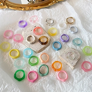 Flat lay of colorful resin and metal rings on a white fabric and stone background