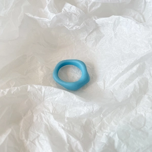 Close-up of matte blue irregular resin ring with wavy organic structure on white background