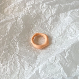 Close-up of a matte orange resin ring with an organic irregular wavy design for women