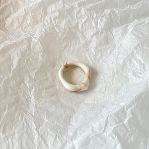 Close-up of resin ring featuring cream and brown marble texture with irregular wave design