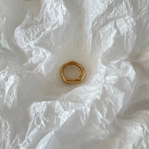 Minimalist golden ring with irregular liquid lava texture on white paper background