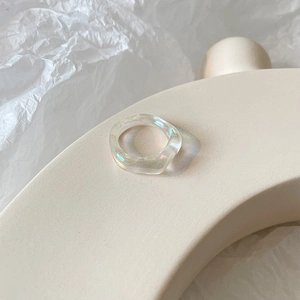 Irregular candy colored resin ring with aurora luster on minimalist paper backdrop