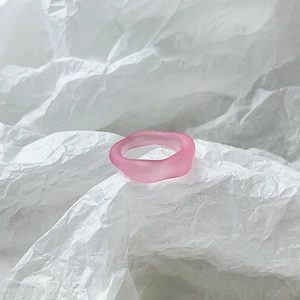 Detailed view of a matte pink resin ring with a unique wavy texture on white paper