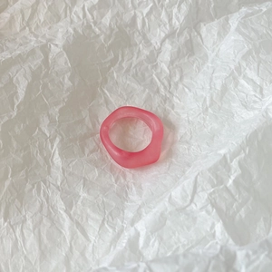 Top view of pink frosted resin ring with wave design on textured white background