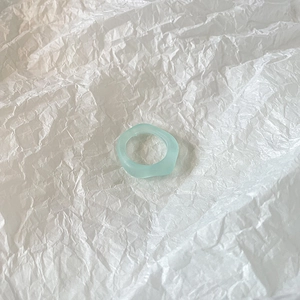Artistic wavy light blue resin ring with matte finish on textured paper background