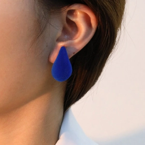 Close-up of a model wearing Klein blue flocked waterdrop studs in s925 silver