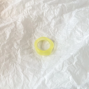 Top view of a pale yellow translucent resin ring with irregular geometric twisted shape
