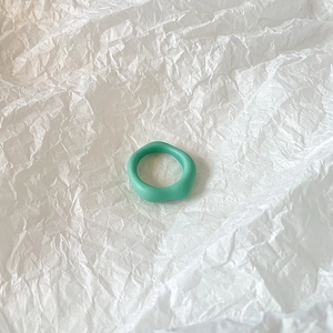 Detail shot of mint green irregular wavy resin ring on white textured background