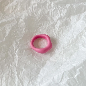 Close-up of pink irregular resin ring with matte finish on white textured background