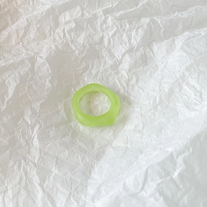 Macro shot of transparent green wavy resin ring on white textured artistic paper