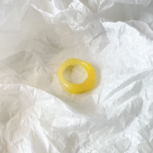 Detail view of a translucent yellow resin ring with a trendy irregular wavy design