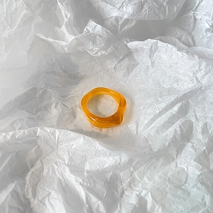 Close-up of translucent amber resin ring with organic irregular design on white paper