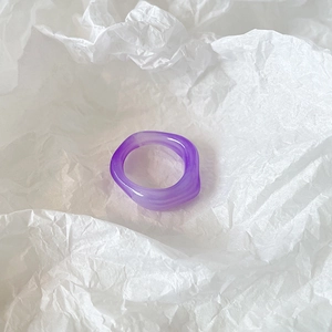 Detail of purple wavy resin ring with translucent marble texture on white paper background