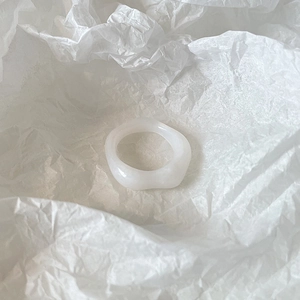 Detail of a minimalist translucent white resin ring featuring an irregular wavy edge design