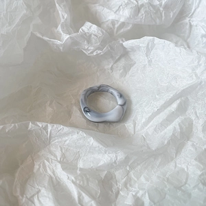 Artistic marble textured resin ring with irregular wave design on white textured paper