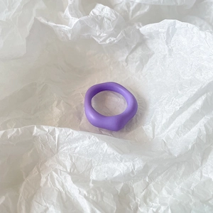 Close-up of a matte purple irregular resin ring placed on white wrinkled paper background