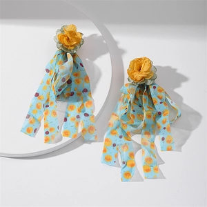 Detailed shot of yellow fabric rose earrings with long blue chiffon floral tassels