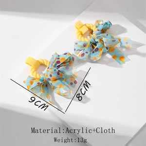 Detail of blue floral fabric bow earrings with yellow acrylic rings and 9cm size marking