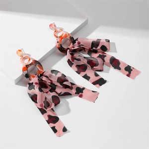 Detailed shot of long bow earrings with resin rings and leopard print silk tassels