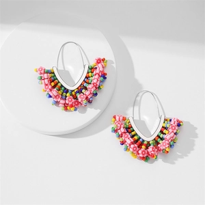 Détail des boucles d'oreilles à pompons en perles colorées avec des accents floraux