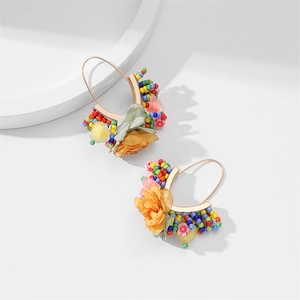 Détail de boucles d'oreilles en perles avec grandes fleurs en tissu et breloques cœur