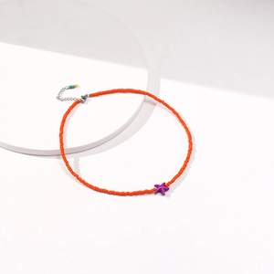 Detailed shot of orange beaded beach necklace featuring a purple starfish pendant and clasp