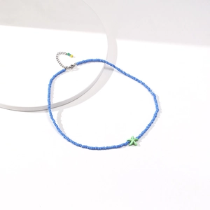 Close-up of handmade blue seed bead choker with a green starfish pendant and metal chain