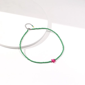 Macro shot of green seed bead necklace featuring a pink starfish pendant and metal clasp