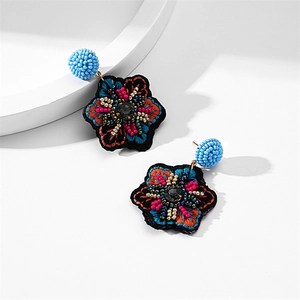 Macro shot of boho floral embroidery earrings with vibrant beads and faceted black gems