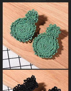Detailed view of handmade green and black beaded earrings with woven disc texture