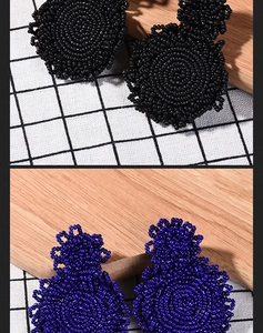 Detail of handmade beaded earrings showing intricate blue and black bohemian patterns