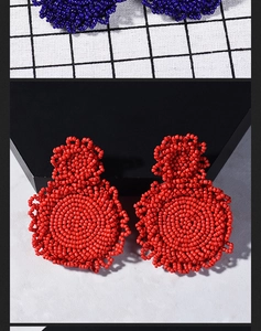 Macro view of handmade woven seed bead disk earrings in vibrant red and blue colors