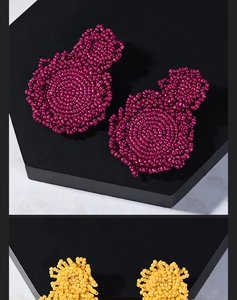 Macro detail of handmade beaded spiral disc earrings in magenta and bright yellow