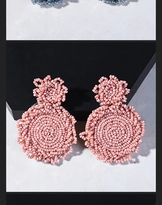 Detailed shot of handmade pink beaded bohemian earrings with intricate woven patterns