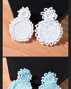 Detail of handmade bohemian beaded hoop earrings in white and light blue textures
