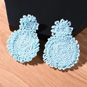 Handmade blue beaded drop earrings in bohemian style on a geometric jewelry stand