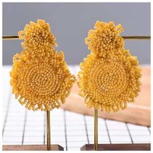 Handmade yellow seed bead earrings in a circular woven ethnic style on display stand