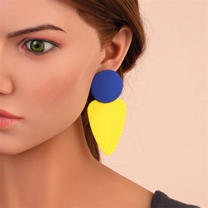 Vue détaillée de longues boucles d'oreilles géométriques, clous bleus et feuilles jaunes