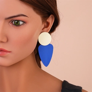 Détail de boucles d'oreilles feuilles bleu roi avec texture mate et clou crème